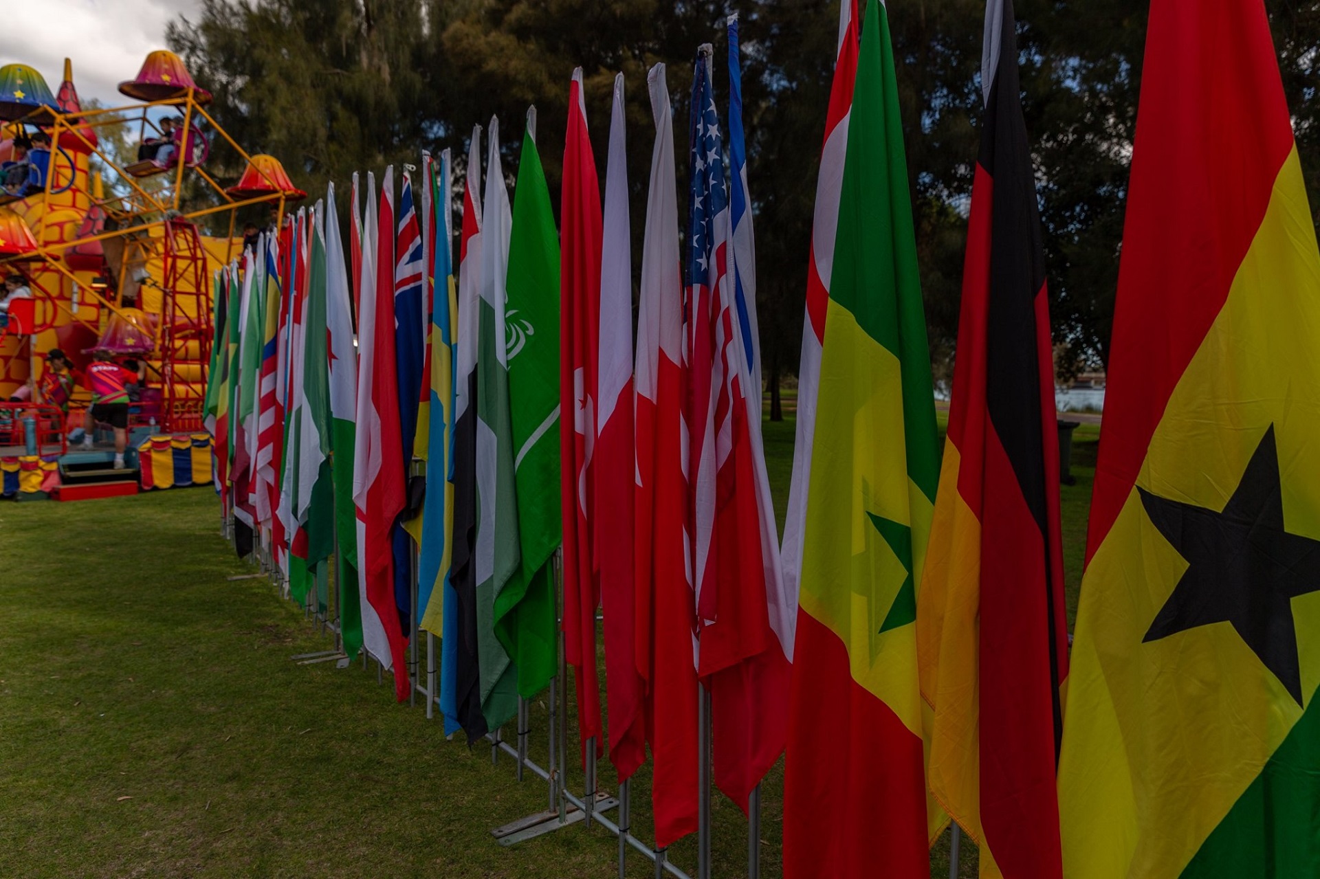 A row of colourful flags from across the world in front of a children's ride